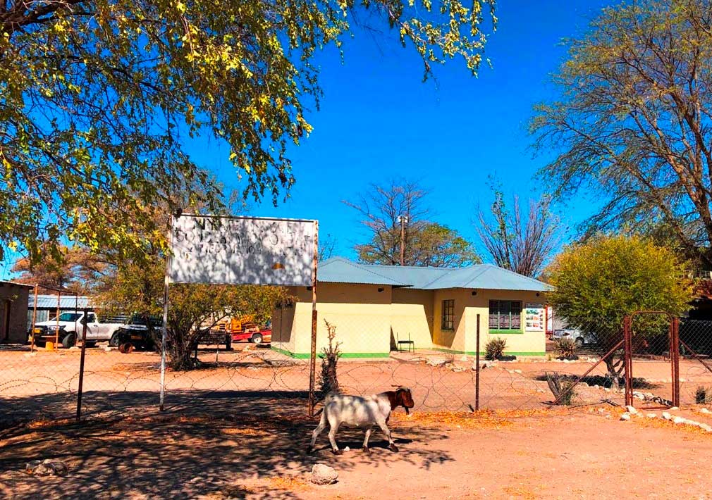 ツムクェ村にあるニャエニャエ保全区・地域森林区事務所。木影の看板の文字は劣化しているが、「Nyae Nyae Conservancy Office & Information Centre」と書いてある © 岡部一明